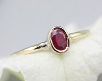 A captivating oval natural red star ruby ring set in a silver bezel setting, elegantly mounted on a sterling silver band. The deep red color of the ruby gemstone shines brilliantly, exuding a sense of mystery and enchantment.